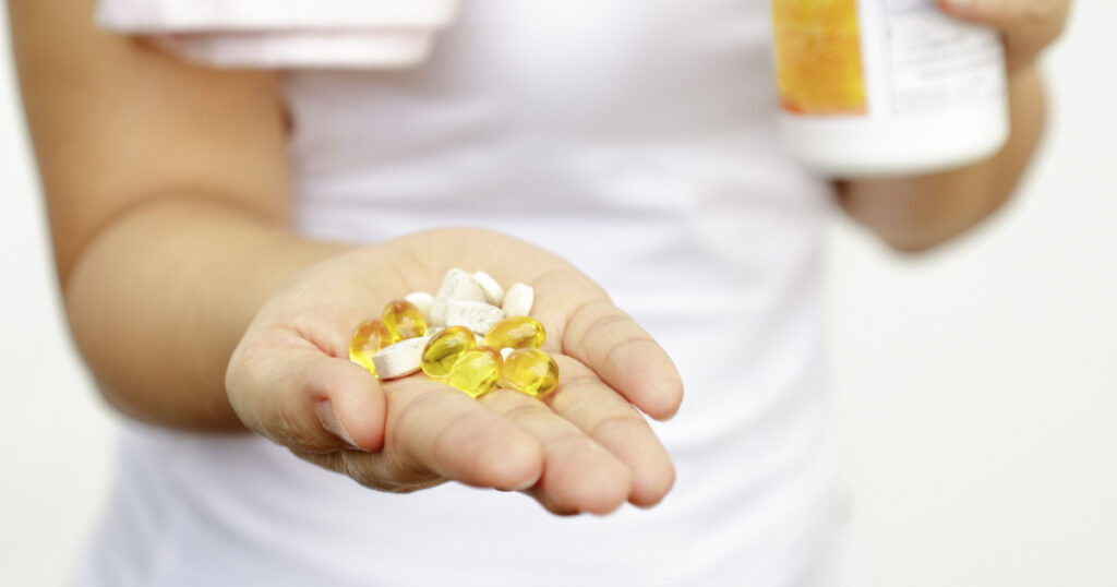 sport and diet concept - woman hand with vitamins and medication
