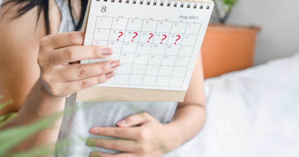 woman hand holding calendar with question mark waiting for late blood period, amenorrhea, irregular periods concept
