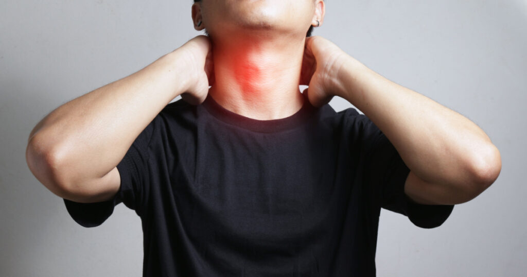 Man suffering he touching inflammated zone on his neck on gray background with health and medical concept.
