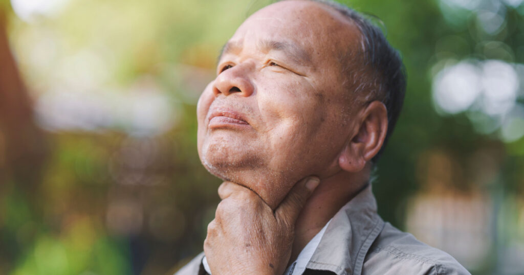 An elderly man has a sore throat due to flu or COVID-19. Concept of sickness of the elderly.
