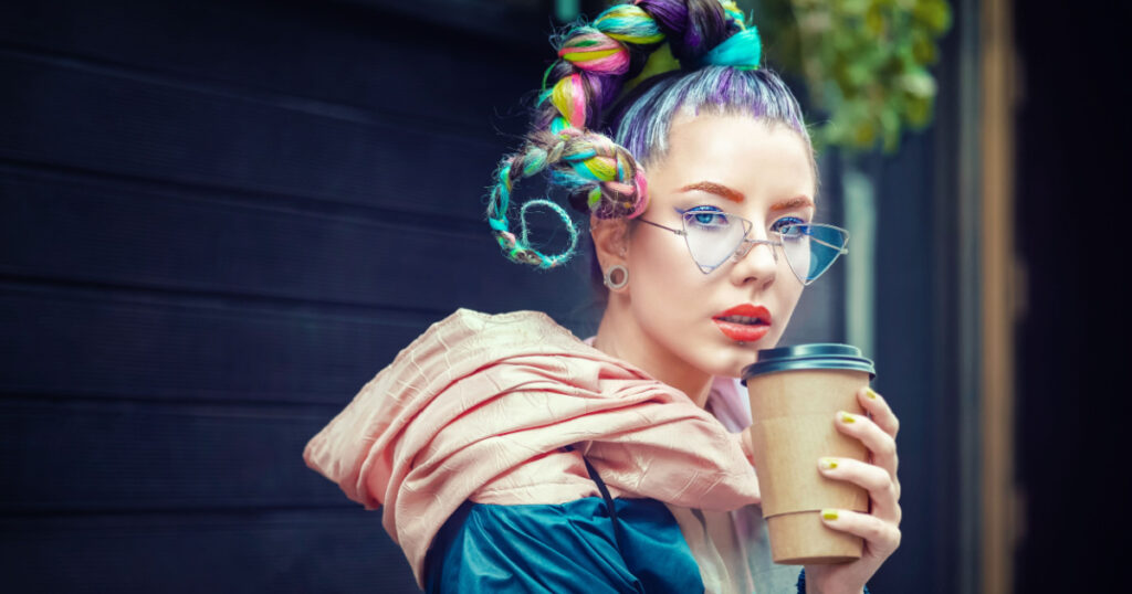 Cool funky young girl with piercing and crazy hair enjoy takeaway coffee on street – Hipster woman with trendy colorful avant-garde look and modern sunglasses having fun outdoor
