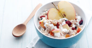 34 Foods That Give You Longer Lasting Energy Than Coffee oatmeal with apple and a wooden spoon