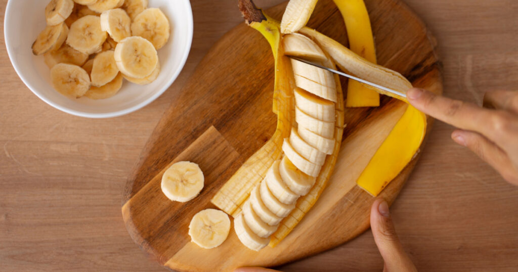 woman cutting banana slices. sliced banana. banana slices. preparing fruit salad. healthy foods.
