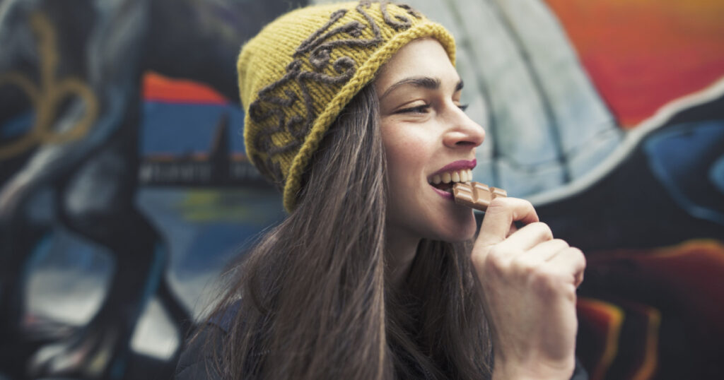 candid image of a beautiful young woman biting a chocolate bar
