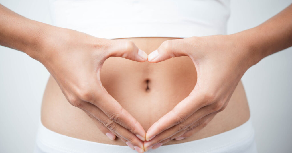 Close up of woman's hands made heart on belly isolated on white background.health care concept.
