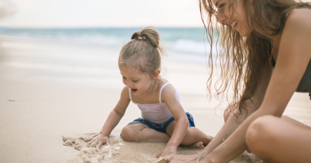 Day. Mom and happy baby playing near the beach