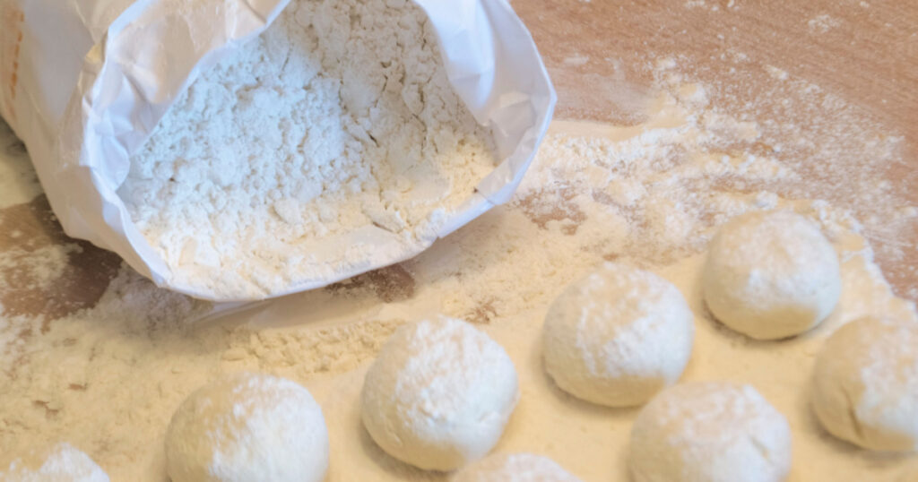 wheat flour in a white package and soft dough for baking, cheesecakes and bread. knead and sculpt the dough. soft focus.
