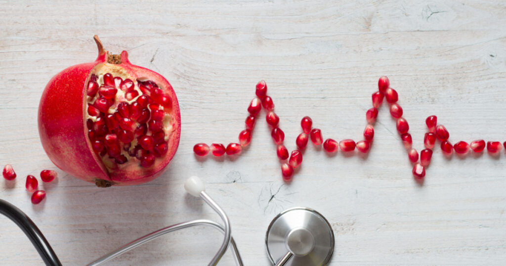 Fruit pomegranate, stethoscope and ECG cardiogram from pomegranate seeds, healthy heart diet concept abstract
