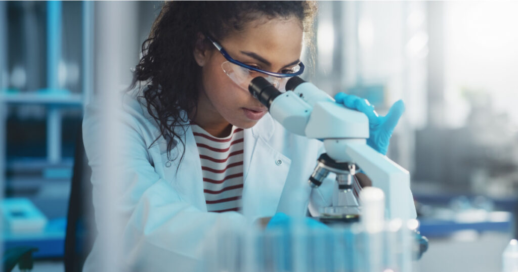 Medical Science Laboratory: Portrait of Beautiful Black Scientist Looking Under Microscope Does Analysis of Test Sample. Ambitious Young Biotechnology Specialist, working with Advanced Equipment
