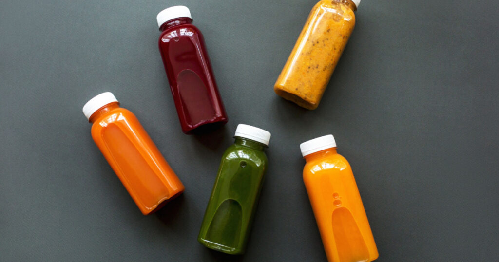 Fresh juices or cocktails of fruits and vegetables in bottles on a gray background. The concept of a healthy diet or detox
