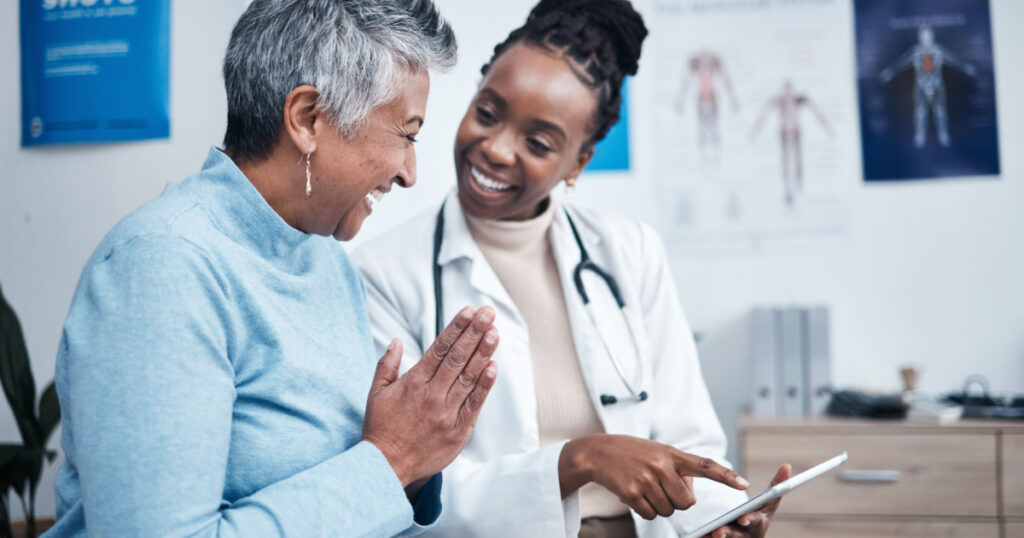 Black woman, doctor and elderly patient with good news, tablet and results for health, advice and report. Happy african medic, mobile touchscreen or healthcare with smile, tech or support in hospital
