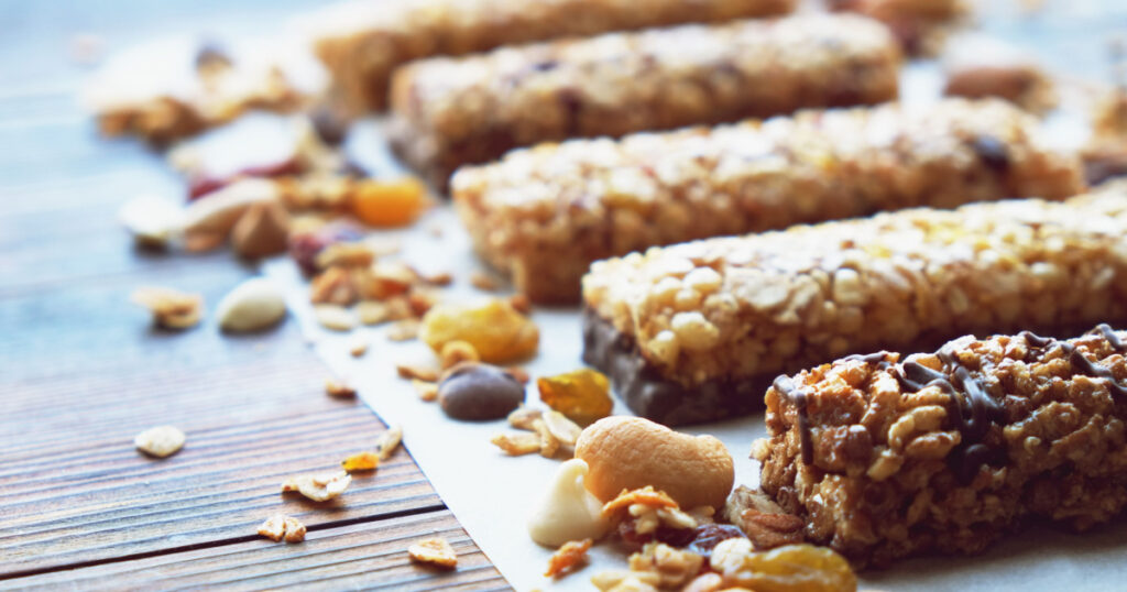 Healthy bars with nuts, seeds and dried fruits on the wooden table, with copy space.
