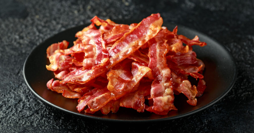 Fried crunchy Streaky Bacon pieces in a black plate
