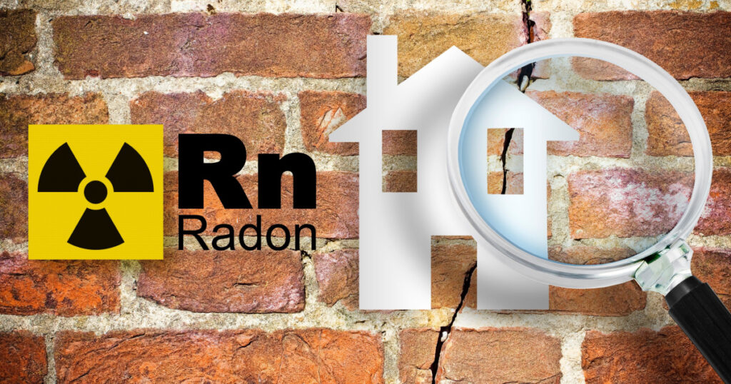 The danger of radon gas in our homes - concept with periodic table of the elements, radioactive warning symbol and home silhouette seen through a magnifying glass against a cracked brick wal
