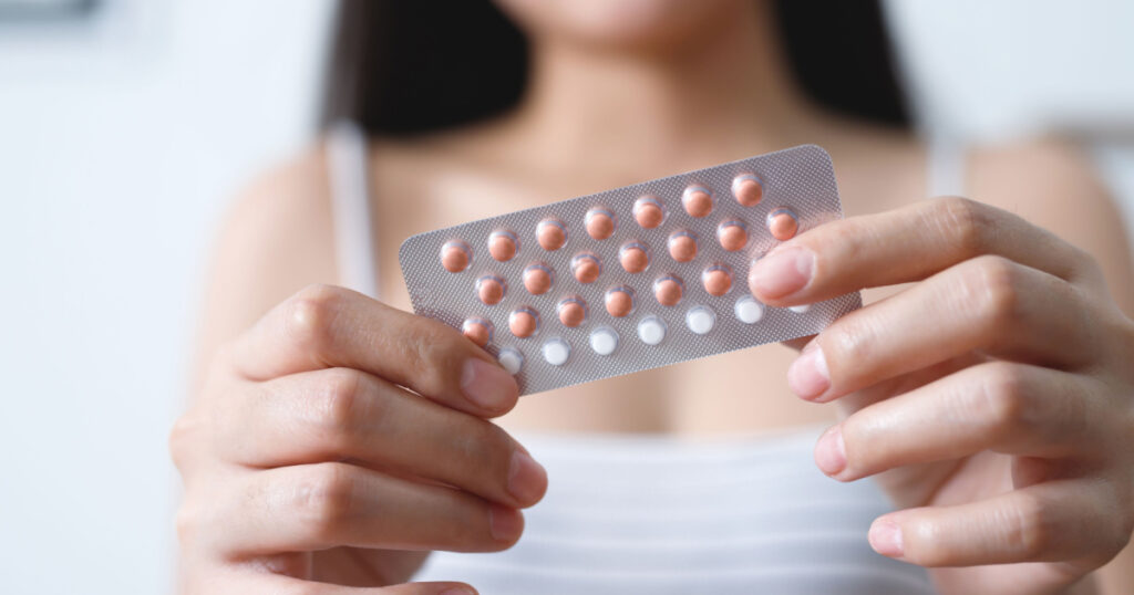 Woman hands opening birth control pills in hand. eating Contraceptive pill. Contraception reduces childbirth and pregnancy concept.
