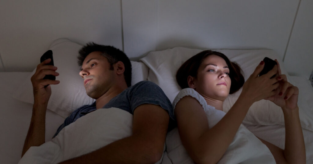 Young couple with smartphones in their bed
