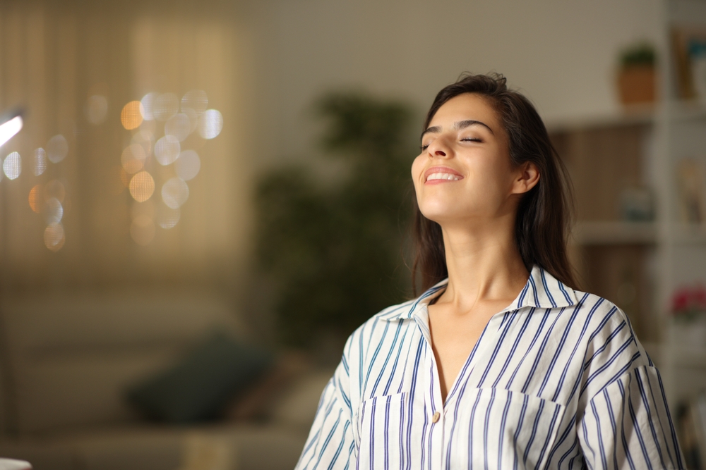 Happy woman breathing fresh air in the night at home