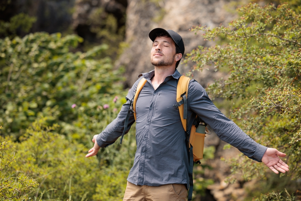 Young man enjoying nature, breathing deeply the fresh air. Let's take care of our natural surroundings and our environment. Moments of disconnection and relaxation