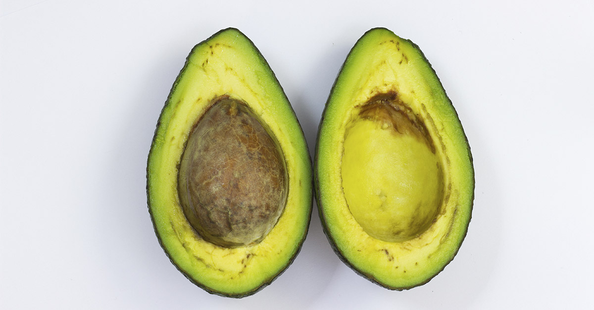 sliced open avocado revealing pit and brown spots