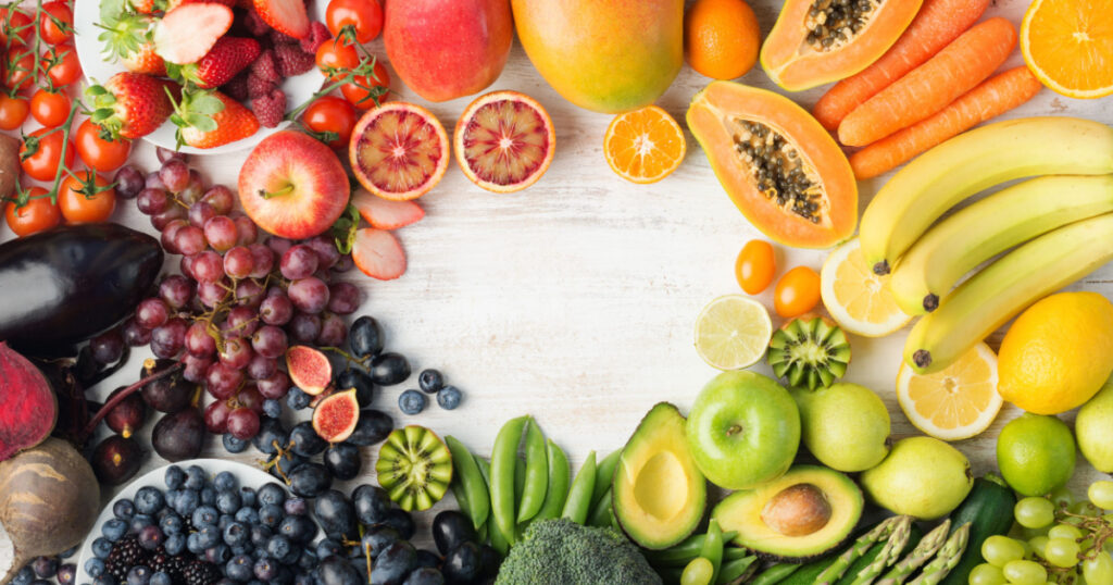 Healthy eating, varieity of fruits and vegetables in rainbow colours on the off white table arranged in a frame with copy space, vertical top view, selective focus
