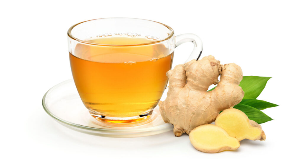 Glass cup of hot ginger tea with ginger rhizome (root) sliced isolated on white background.