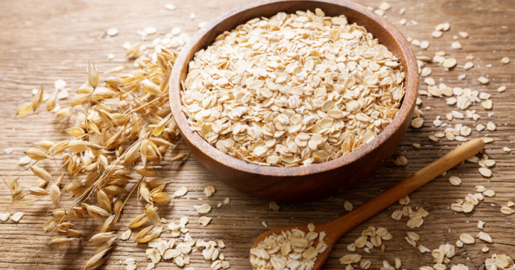 oatmeal flakes and ears of oat on wooden table