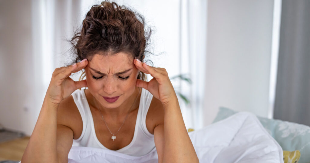 Young woman on bed, headache. Vertigo illness concept. Woman hands on his head felling headache dizzy sense of spinning dizziness,a problem with the inner ear, brain, or sensory nerve pathway.