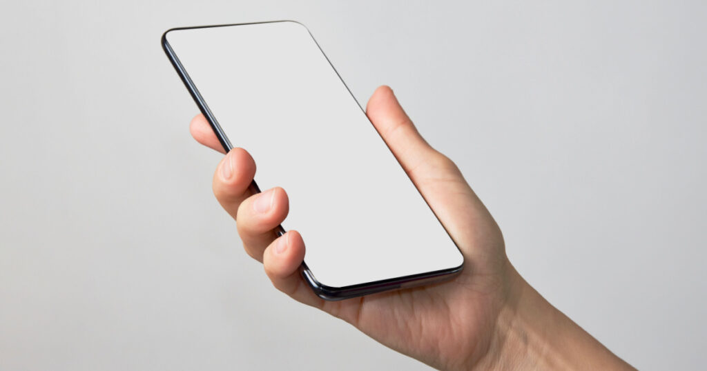 Woman hand holding phone on white background with copy space. Woman holding smartphone with white screen. Hand with blank cellphone display, close-up