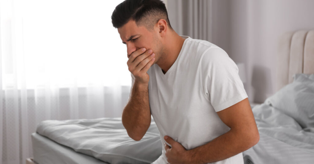 Man suffering from nausea on bed at home. Food poisoning