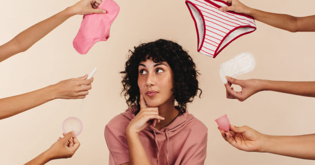 Young woman contemplating the best sanitary choice for her body. Thoughtful young woman looking away while surrounded by hands holding different reusable and non-reusable sanitary products.
