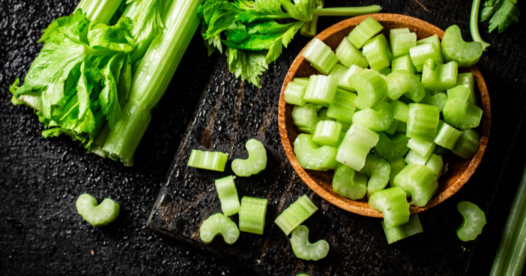 Pieces of celery in a wooden plate on the table. On a black background. High quality photo