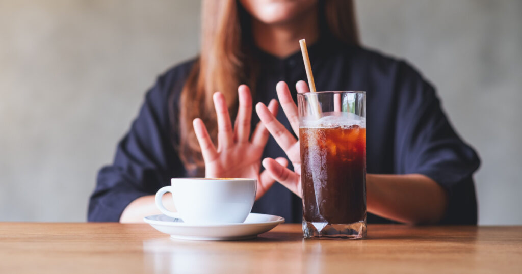 A young woman making hand sign to refuse iced coffee and hot coffee
