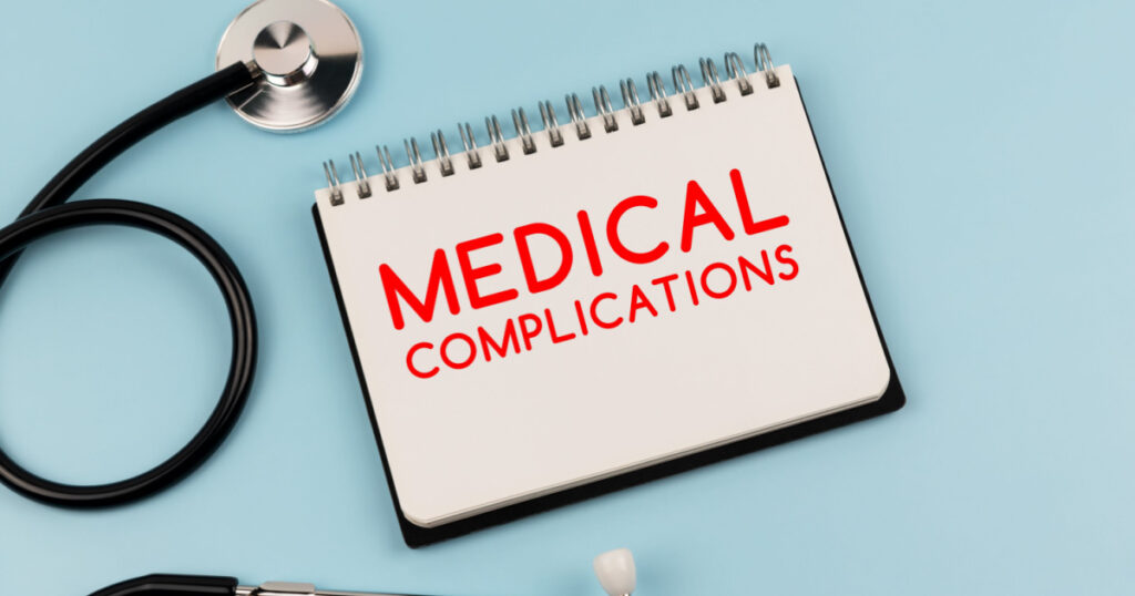 Medical complications text on note pad and stethoscope