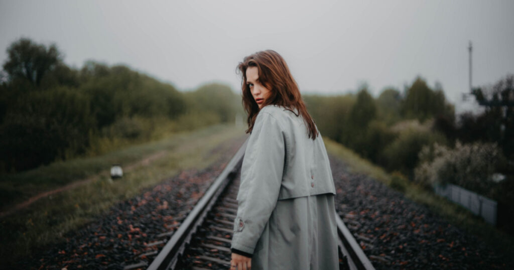 woman looking over shoulder on train track