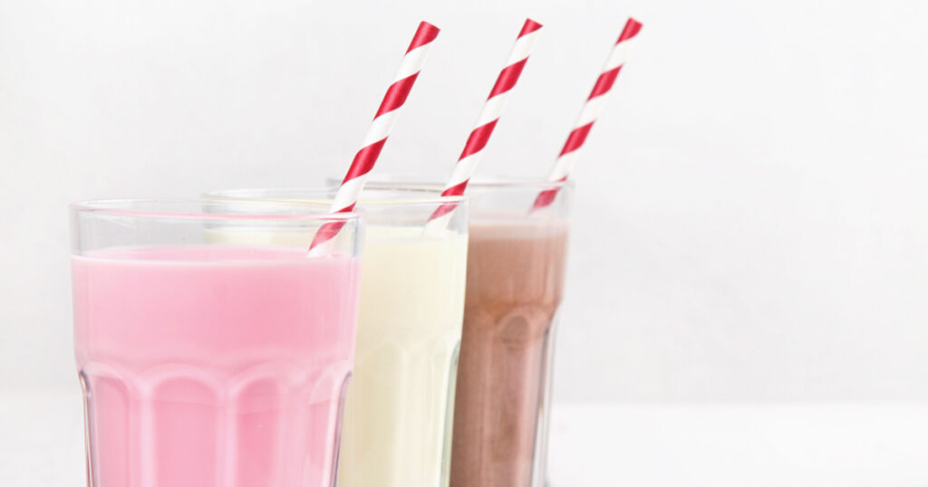 Milkshakes with chocolate, strawberry, banana flavor on a white wooden background
