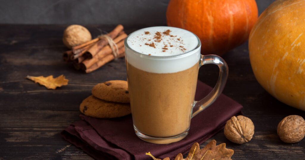 Pumpkin Spice Latte. Cup of Latte with Seasonal Autumn Spices, Cookies and Fall Decor. Traditional Coffee Drink for Autumn Holidays.
