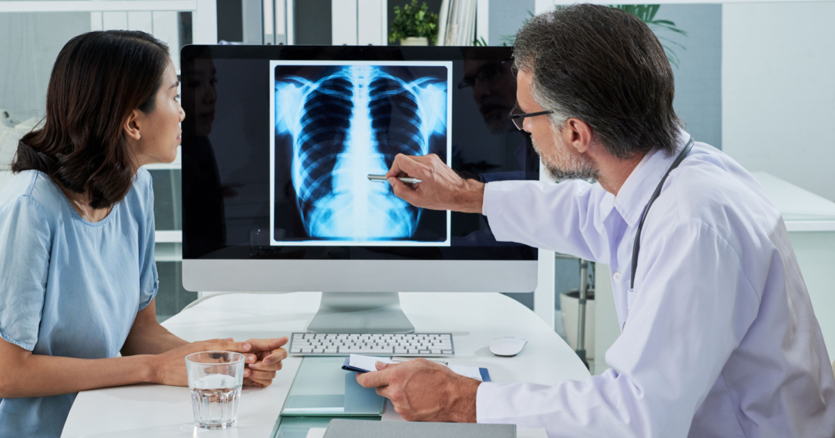 Doctor explaining lungs x-ray on computer screen to young patient