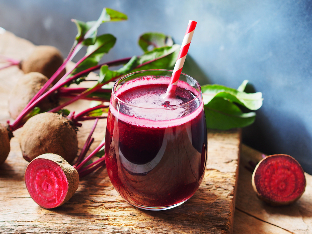 Beetroot juice in a glass and fresh organics beetroot on rustic wooden table for refreshing drinks concept.
