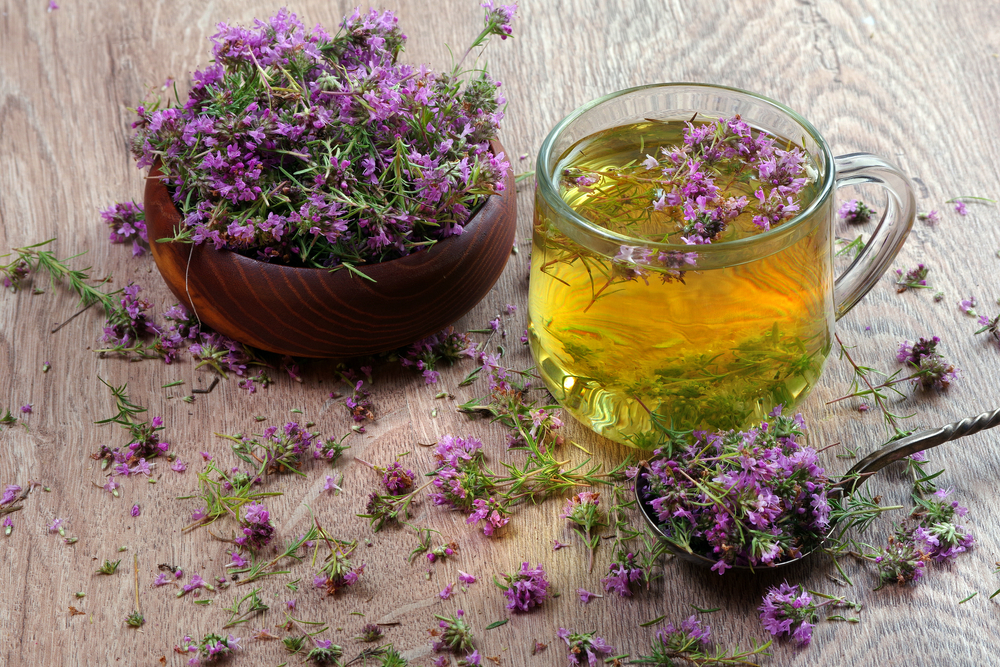 summer medicinal herbs. thyme tea on a wooden table. fresh thyme flowers in a spoon
