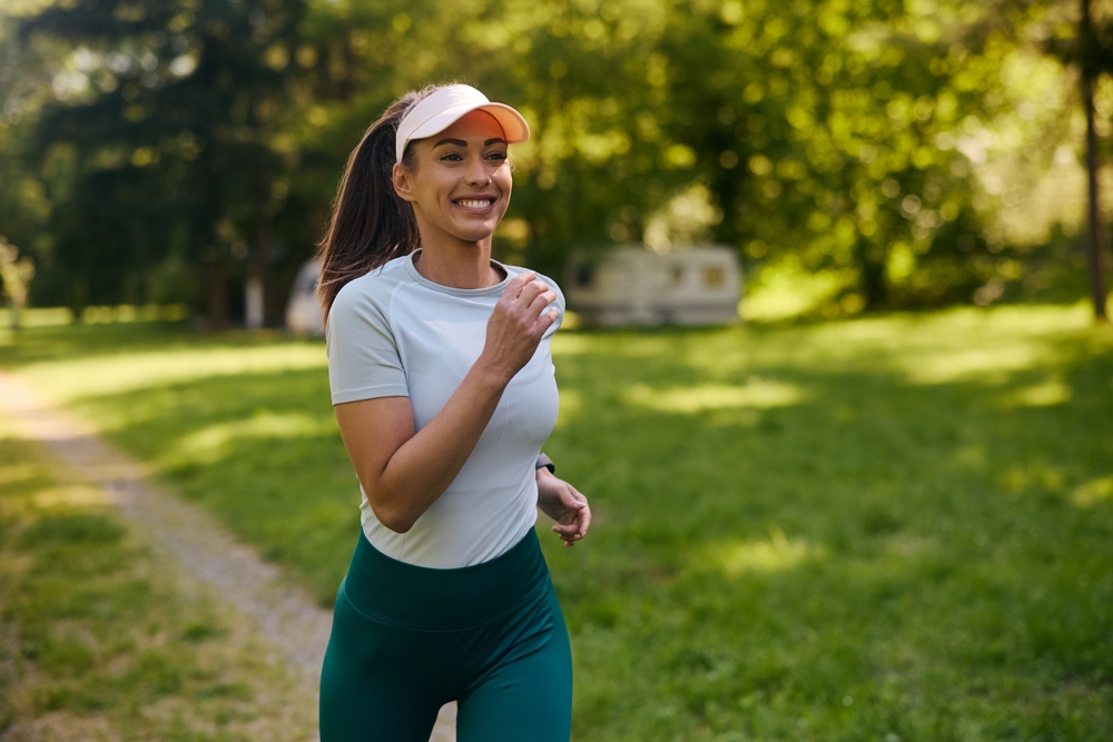 Happy athletic woman running while exercising in nature. Copy space.