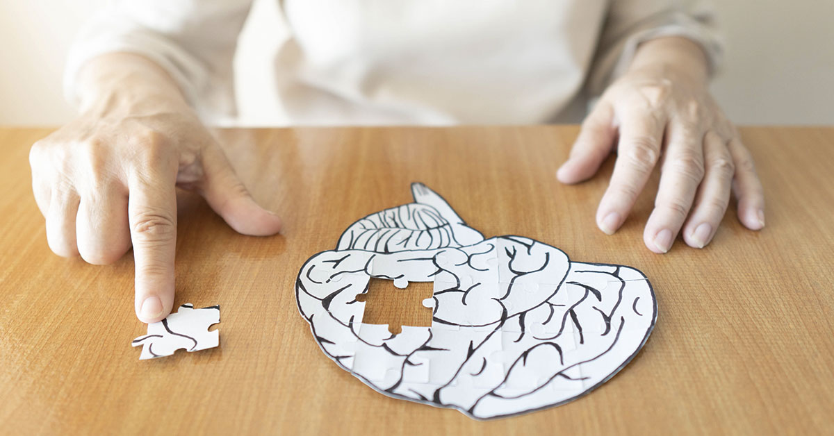 Person putting a puzzle of a brain together. Alzheimer's Disease concept