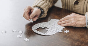 This Common Daily Habit May be a Symptom of Dementia putting together puzzle of head. Dementia conceptc