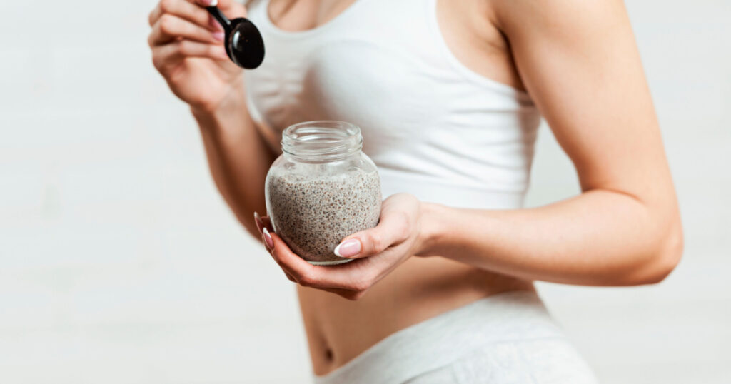 Fit, attractive woman holding a glass jar of chia pudding
