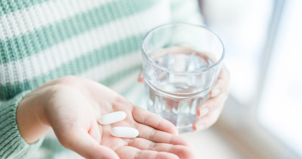 Close Up Of Girl holding Pill and glass of water.With Paracetamol.Nutritional Supplements.Sport,Diet Concept.Capsules Vitamin And Dietary Supplements.