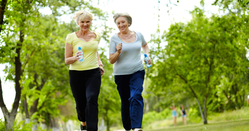 Portrait of two senior females running outdoors