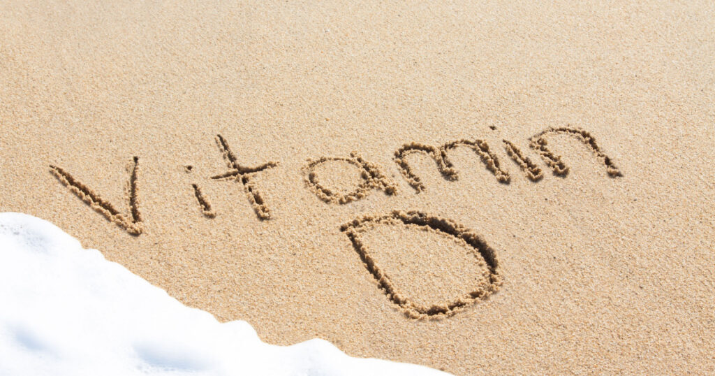 Vitamin D written in the sand with foam from a wave washing up