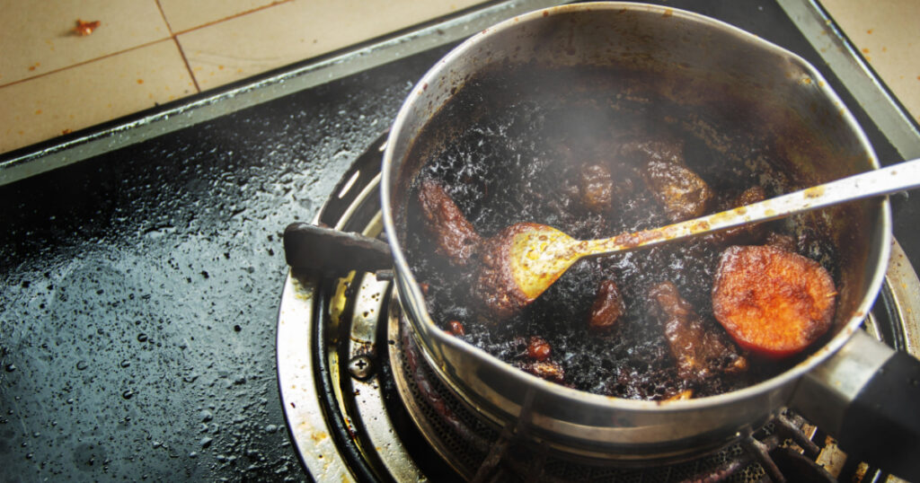 Burned food in the pot on a gas stove and full of oil stains from warming up food that is forgetful.