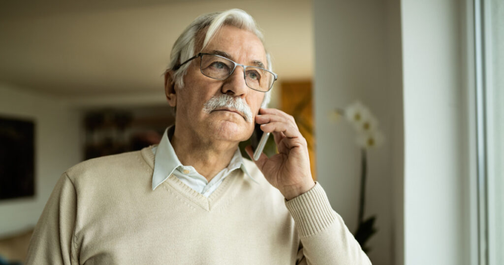Pensive mature man communicating with someone over mobile phone.