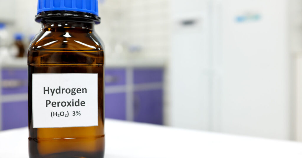 Selective focus of hydrogen peroxide solution in brown amber bottle. Blur laboratory background with copy space.