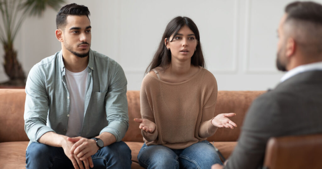 Portrait of serious young lady talking to psychologist counselor complaining on bad relationship with husband, family couple counseling having conversation about problem at therapy session